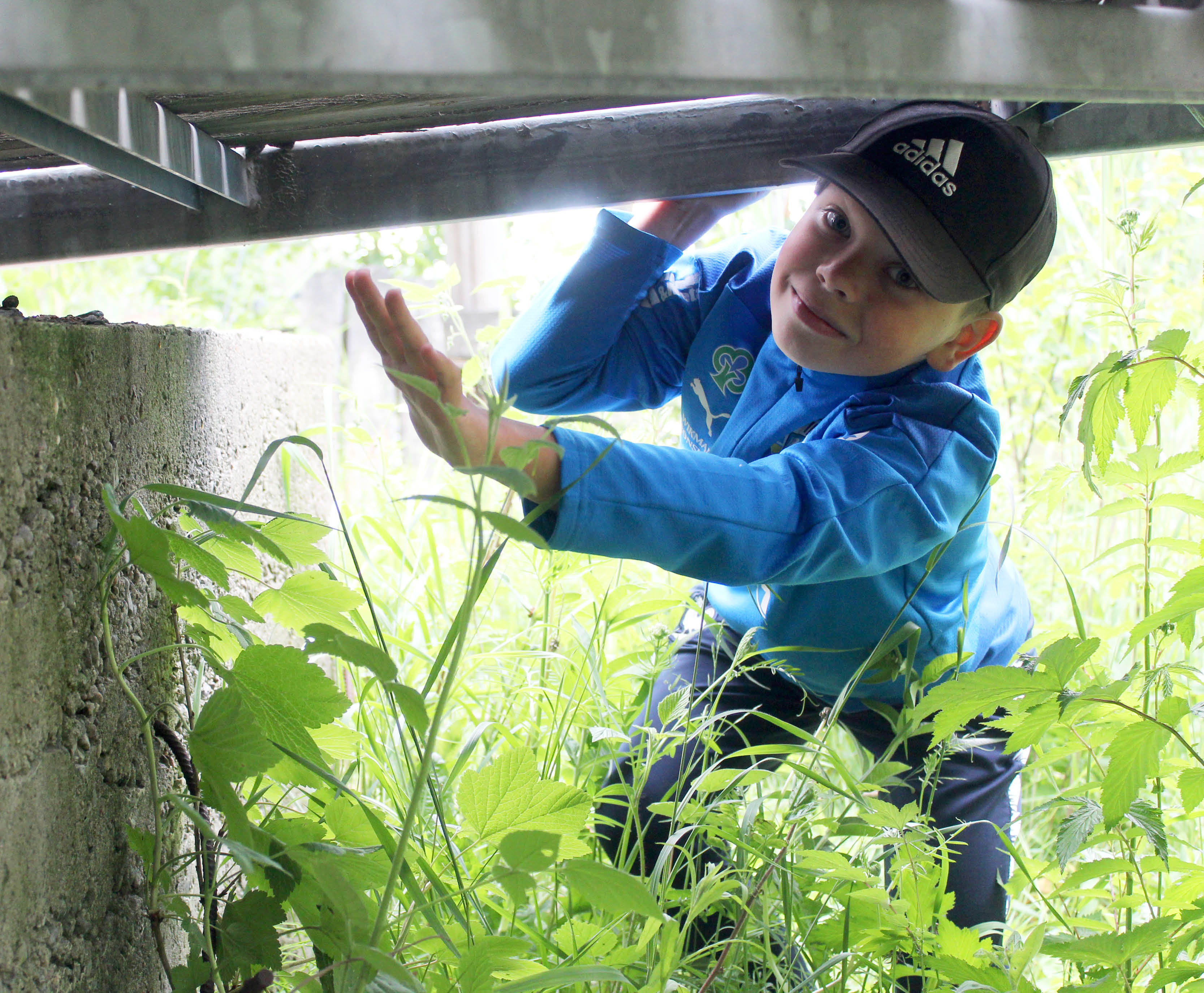 En pojke som letar cacher under en bro.