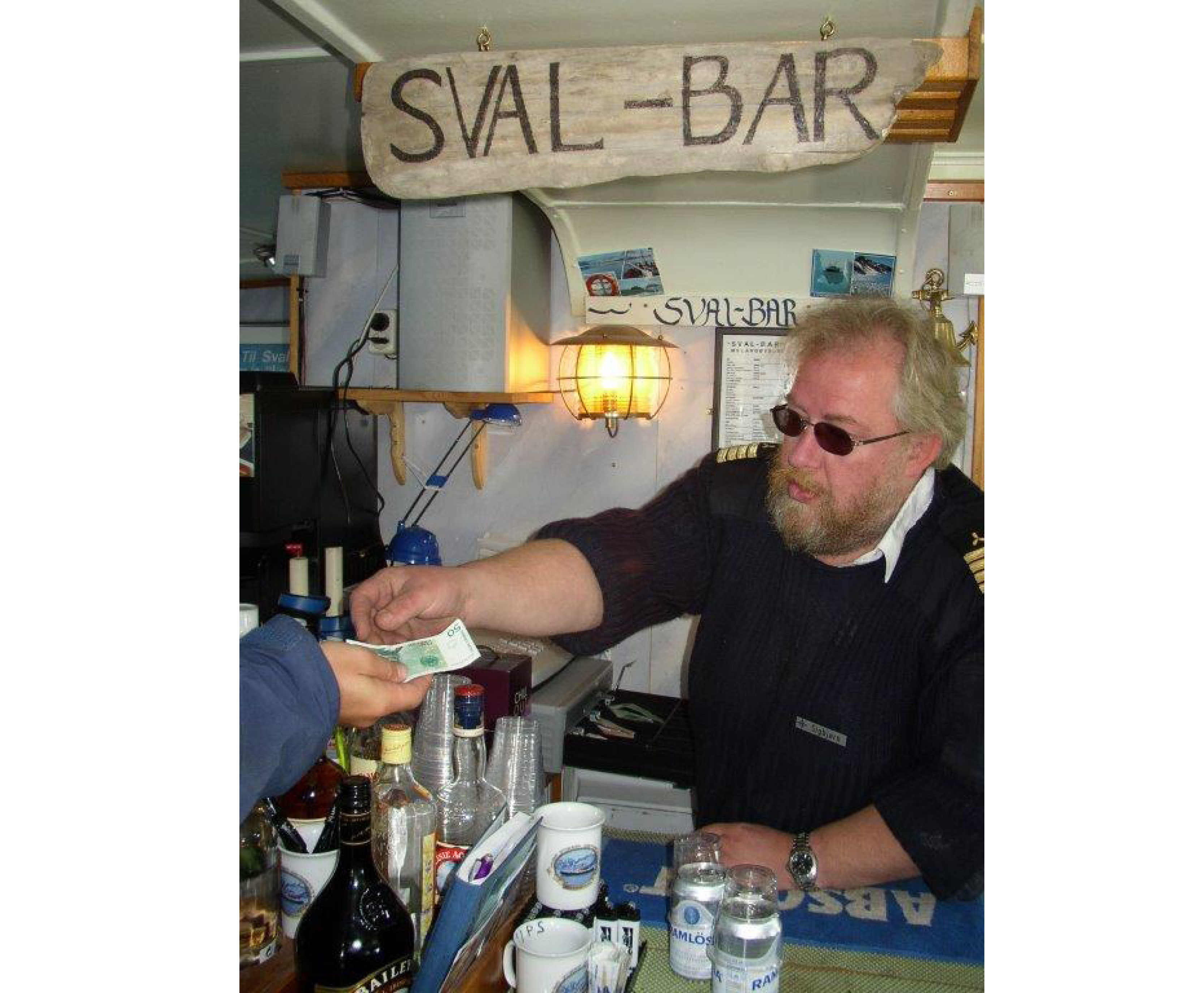 En äldre skäggig man häller upp öl i en bar.