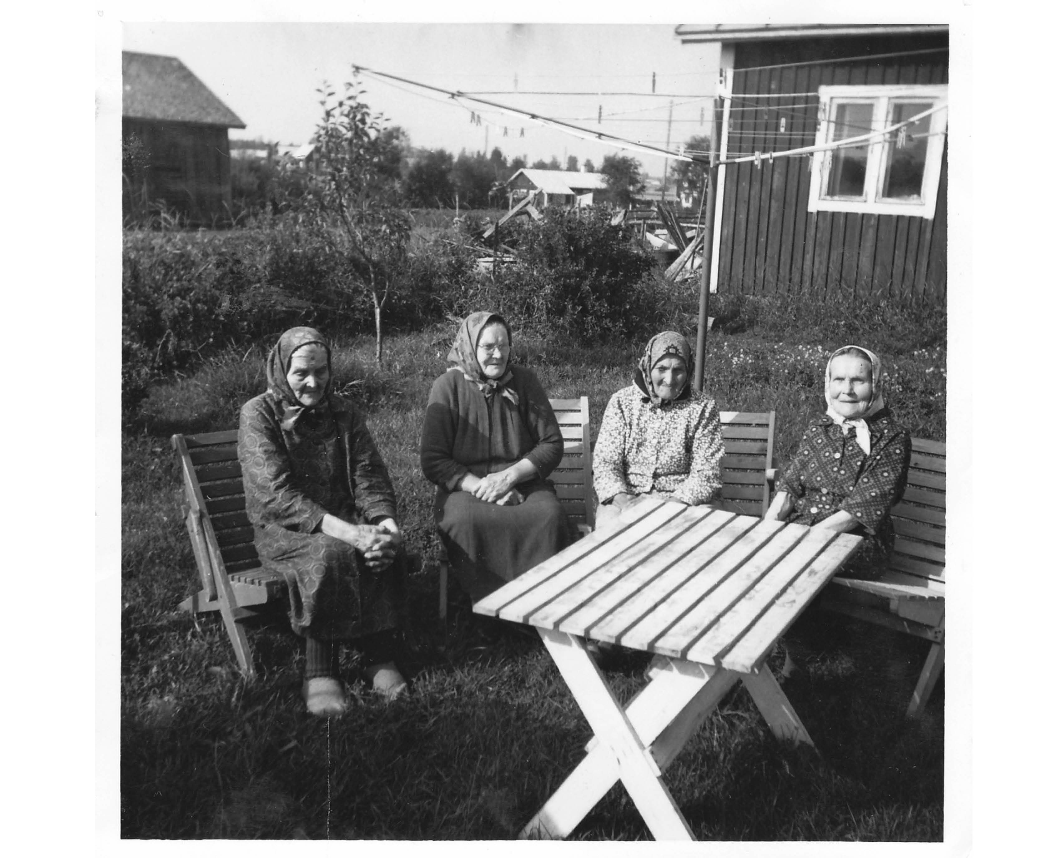 Tre äldre damer i en trädgård.