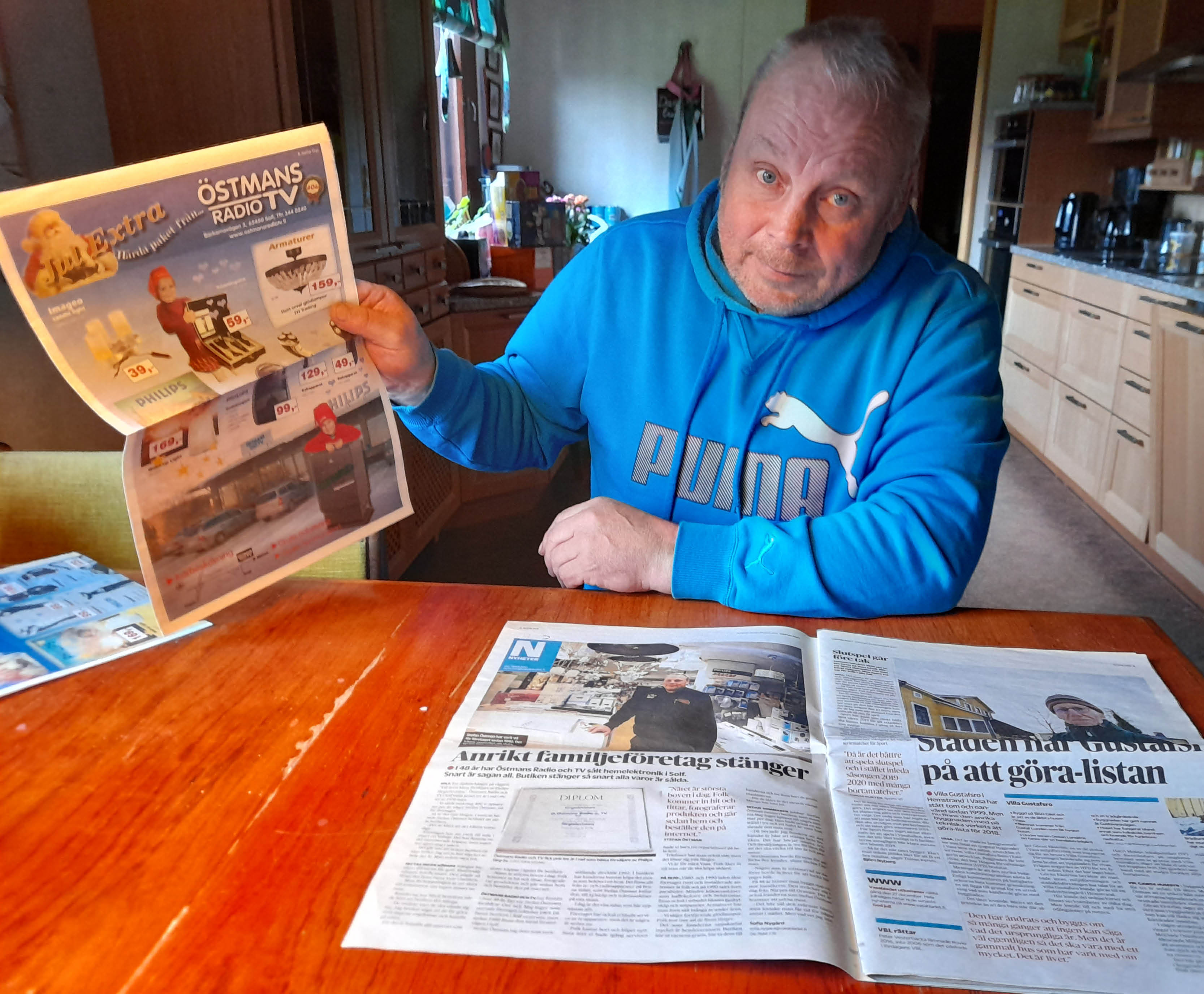 En medelålders man håller upp ett tidningsuppslag