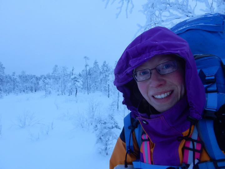 En ung kvinna med ryggsäck i ett snötäckt vinterlandskap.