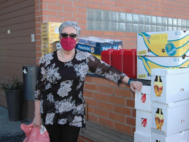 en kvinna framför bananlådor med förnödenheter