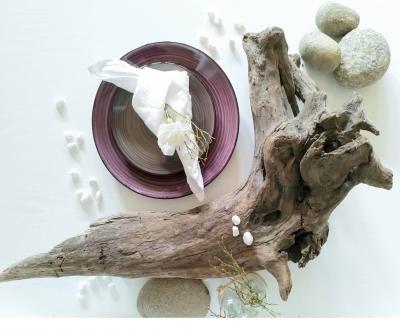 en lila tallrik med en vit servett och en trärot samt fina stenar